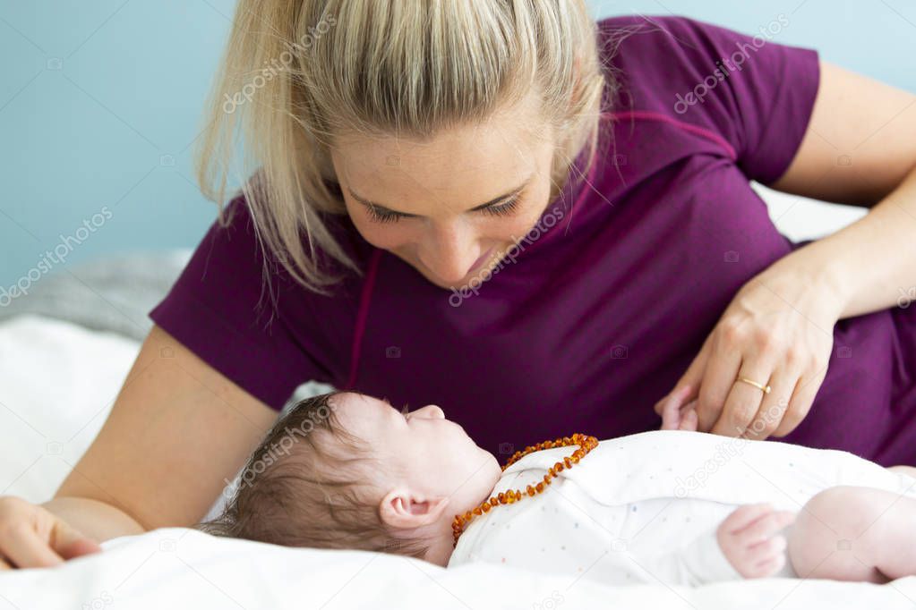 beautiful blond mother with her 3 month old baby wearing a amber necklace