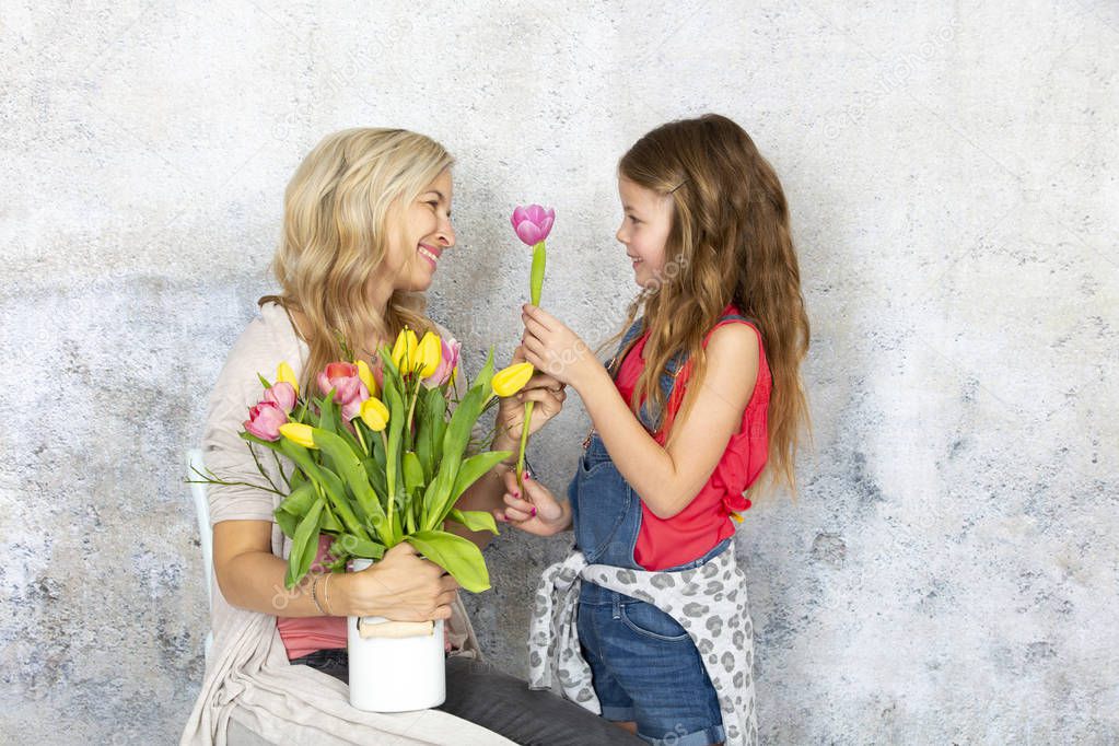 little cute daughter congratulating young mother with bouquet of colorful flowers, Mother day concept  