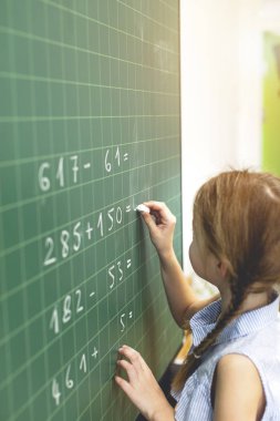 Okul çocuğu sınıftaki tahtaya güveniyor.