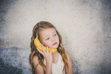 Güzel kız muz gri beton duvar arka plan üzerinde ile telefon görüşmesi yapmak