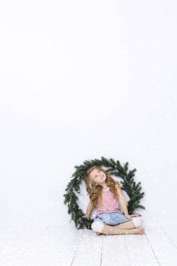 Beyaz arka plan üzerinde izole Noel çelenk ile poz mutlu güzel kız