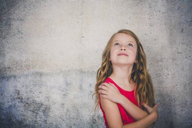 çapraz kolları ile ayakta ve beton arka plan önünde ararken kırmızı bluz sevimli sarışın kız 