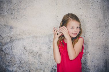 blond beautiful girl talking on corded phone made out of can on concrete wall background clipart