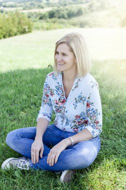 Yaz güneşli gün çayır oturan mutlu memnun kadın