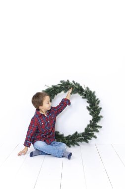 Beyaz arka plan üzerinde izole Noel çelenk ile poz mutlu küçük çocuk