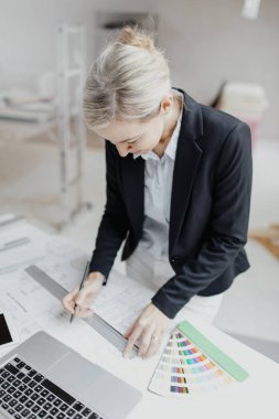 Şantiyedeki takım elbiseli çekici genç bayan mimar planlarla çalışıyor.