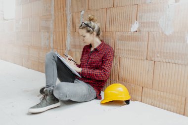 İnşaat alanında not defteri ve sarı miğferli çekici bir bayan mimar.