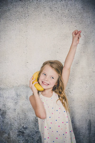 Hübsches Mädchen Telefoniert Mit Banane Auf Grauem Betonwandhintergrund — Stockfoto