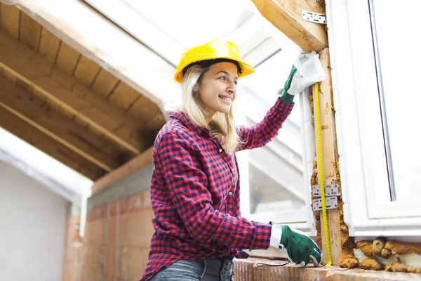 blonde woman with yellow helmet and green gloves planning expansion of loft