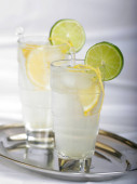 studené letní drink s citronem a limetkou v glasess na stříbrném podnose, detail 