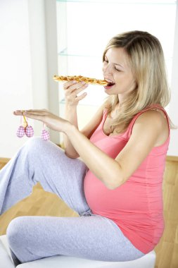 tatlı örgülü Maya ekmek yemek ve Paskalya yumurtaları evde koltukta otururken tutan mutlu hamile kadın