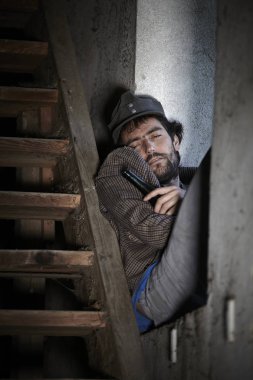  sakallı dilenci alkol cam şişe tutan ve binada merdiven yakınında pencere üzerinde uyku 