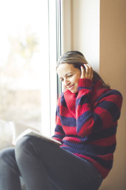 genç güzel kadın pencere kenarında otururken kitap okuma