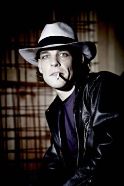 karanlık stüdyo arka planda şapka sigara sigara yakışıklı genç adamın portresi 