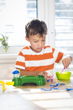 küçük çocuk evde pencere yakınındaki masada otururken renkleri ile deneme