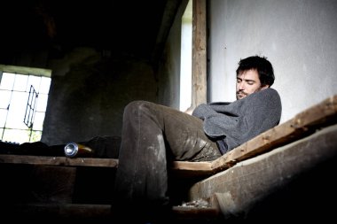 terk edilmiş binada ahşap merdivenlerde uyuyan sarhoş evsiz adam 