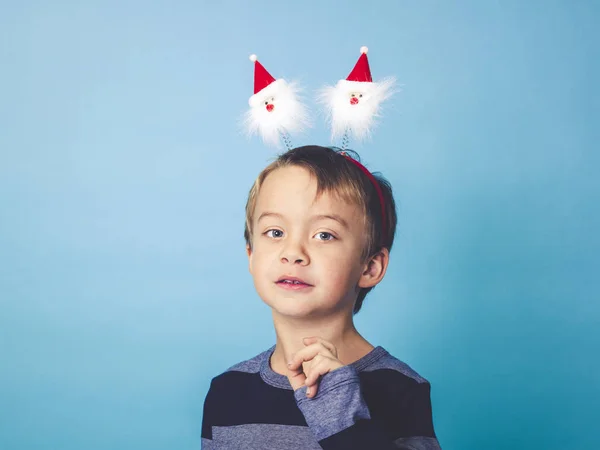 新年コンセプト ブルー スタジオ背景の前でポーズの頭の上のクリスマスの装飾を持った少年 — ストック写真