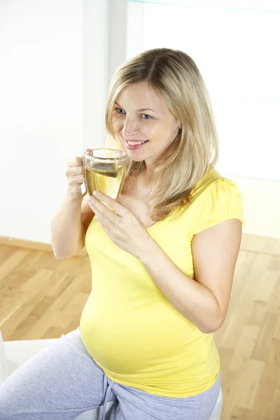 Счастливая Беременная Женщина Сидит Кресле Пьет Чай Стеклянной Чашки Дома — стоковое фото