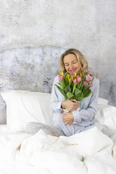 beautiful happy woman with tulips bouquet sitting in bed, Valentine Day concept