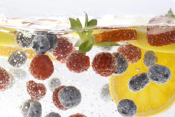 Zitronenscheiben Mit Himbeeren Und Blaubeeren Mit Erdbeere Unter Wasser Auf — Stockfoto