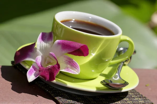 Tasse Kaffee Mit Blume Und Löffel Auf Unscharfem Grünem Hintergrund — Stockfoto