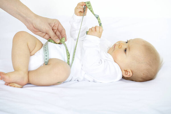Young woman measuring with tape seven month old baby 