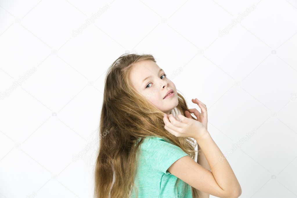happy beautiful little blonde girl in green t-shirt dancing on white studio background 