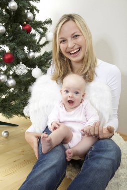 Bebek anne diz dekoratif Noel ağacı yakın oturan beyaz melek kanatlı  