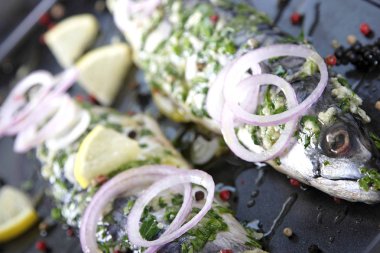 soğan halkaları ve tepsi pişirme üzerinde limon ile balık