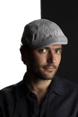 siyah ve beyaz arka planda kamera bakarak kap ve gömlek tıraşsız yakışıklı adam portre 