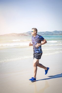 tropik sahilde güneşli gün koşan atletik adam 