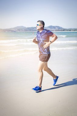 tropik sahilde güneşli gün koşan atletik adam 