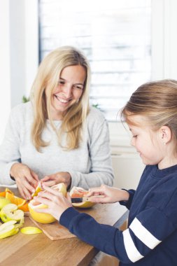 Anne ve kızı mutfakta meyve salatası hazırlarken eğleniyor 