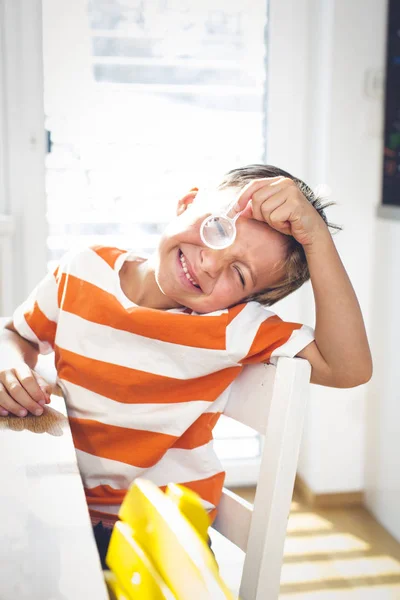 Menino Curioso Sentado Mesa Olhando Através Lupa Enquanto Faz Experiência — Fotografia de Stock