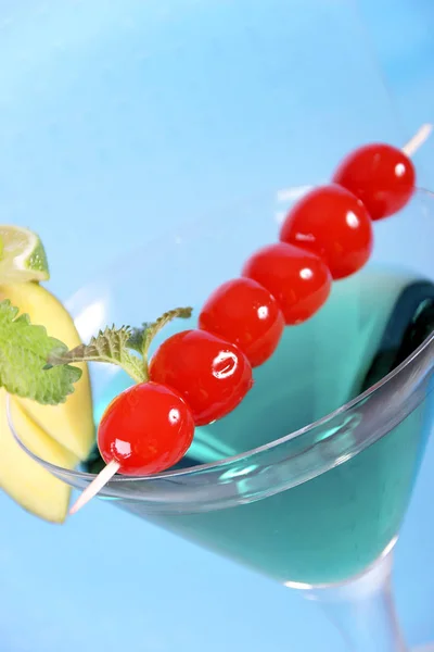 blue cocktail in martini glass with cherries and fruit decoration, close-up