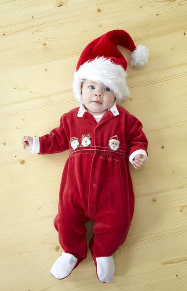 Милый Малыш Красном Костюме Санта Клауса Лежит Деревянном Полу — стоковое фото