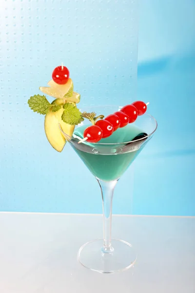 blue cocktail in martini glass with cherries and fruit decoration, close-up