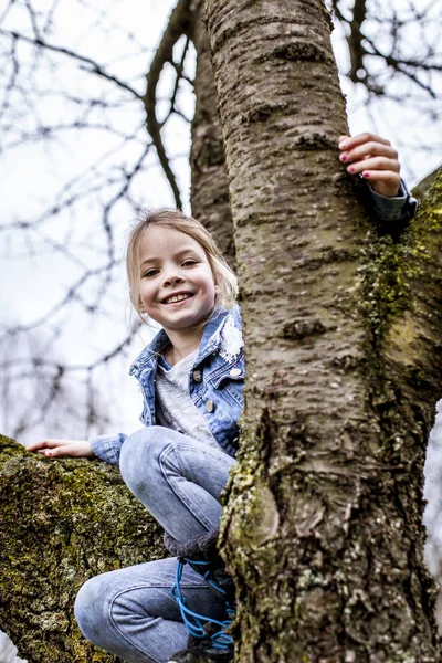 Kleines Schönes Mädchen Sitzt Auf Einem Ast Frühlingspark — Stockfoto