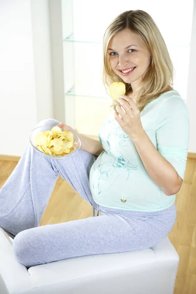 Gelukkig Zwangere Vrouw Zittend Een Stoel Eten Chips Thuis — Stockfoto