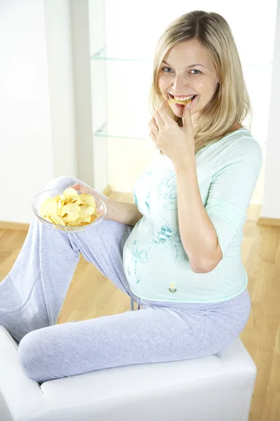 Gelukkig Zwangere Vrouw Zittend Een Stoel Eten Chips Thuis — Stockfoto