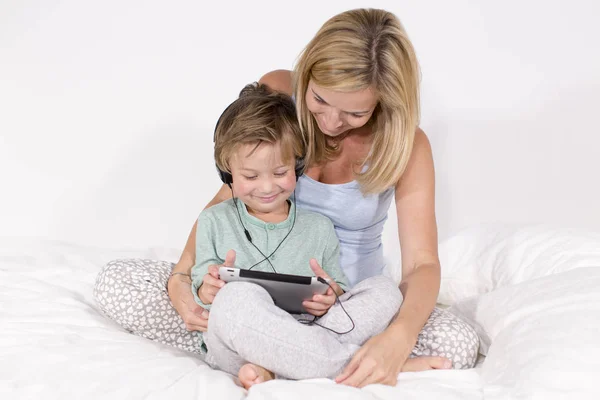 Matka Syn Zabawy Siedząc Słuchawki Komputer Typu Tablet Łóżku — Zdjęcie stockowe