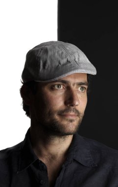 siyah ve beyaz arka planda kenara bakarak Cap ve gömlek tıraşsız yakışıklı adam portre 