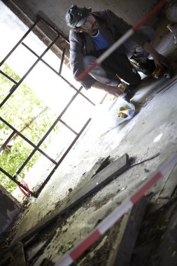 sakallı evsiz adam çömelme ve eski binada kattan boş şişeler toplayarak 