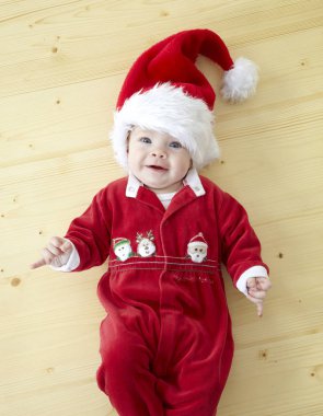 Kırmızı Noel Baba kostüm ahşap yerde yatarken şirin bebek 