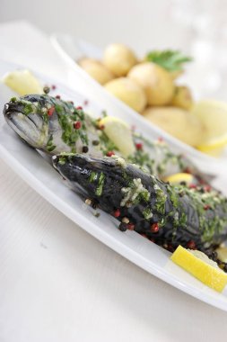 baharat ve beyaz plaka üzerinde limon ile kızarmış balık 