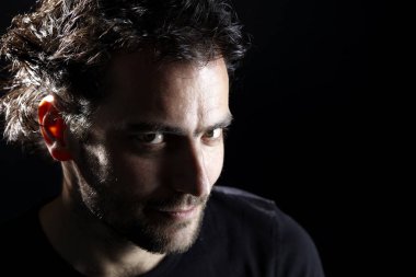 karanlık arka planda kamera bakarak yakışıklı sakallı Brunet adam portre, yakın çekim