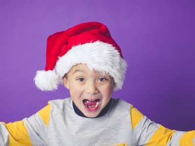 şok çocuk gözleri iri ve açık ağız Menekşe arka planda, Noel kavramı bağırarak ile kırmızı santa şapka  