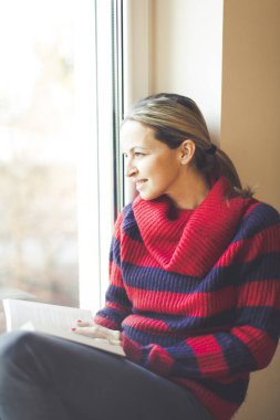 genç güzel kadın pencere kenarında otururken kitap okuma
