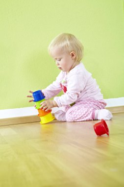 Sevimli küçük bebek çocuk odasında eğleniyor ve oyuncak yapı taşlarıyla oynuyor.