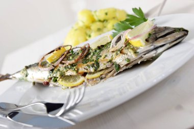 soğan halkaları ve beyaz plaka üzerinde limon ile kızarmış balık 